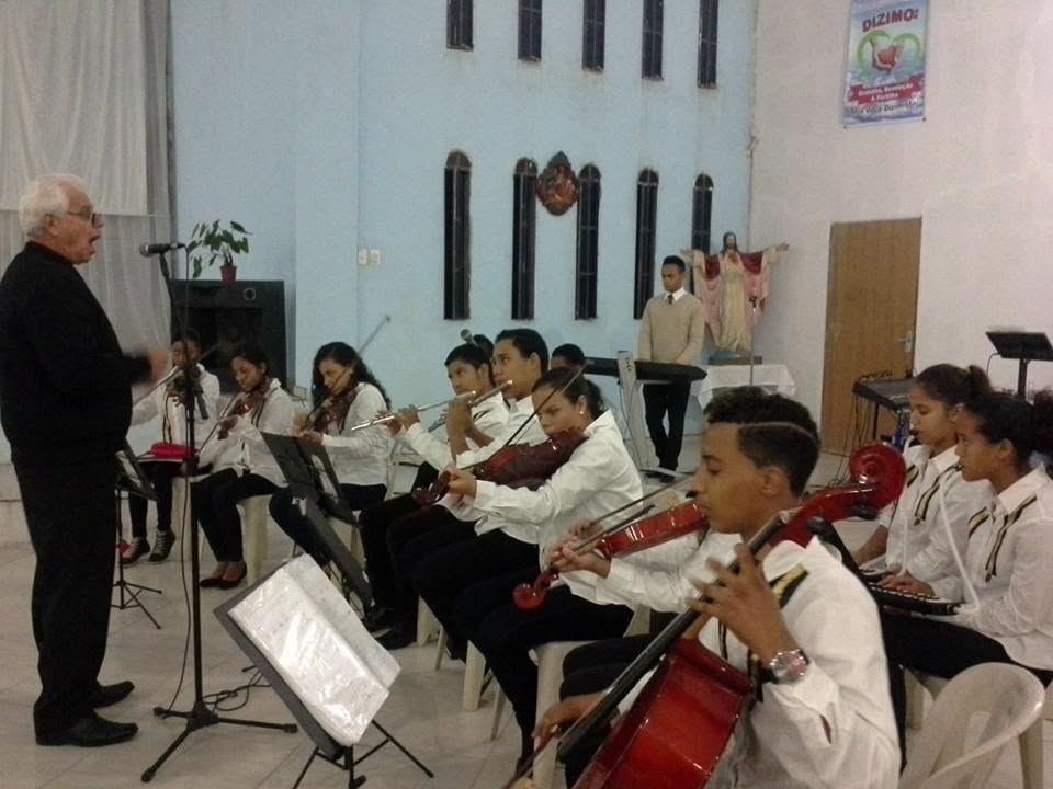Orquestra jovem tocando em igreja sob regência do maestro