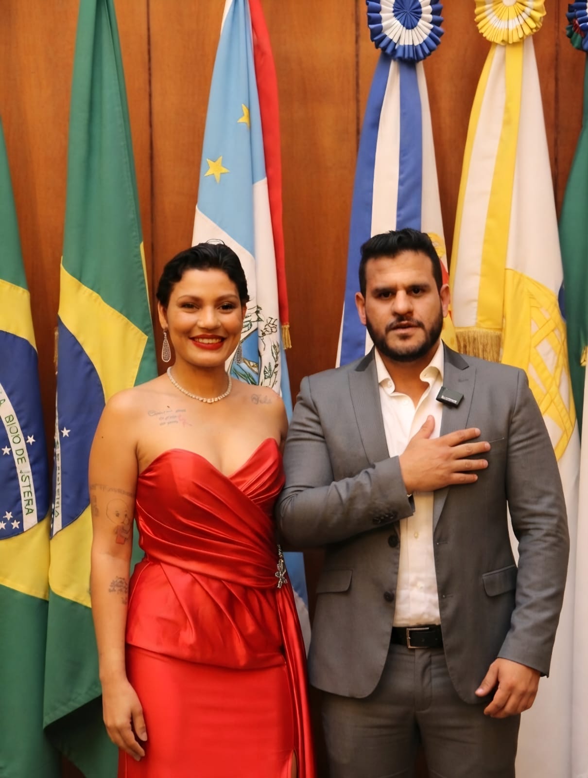 Homenageada de vestido vermelho ao lado do presidente fundador da CAV em sessão solene