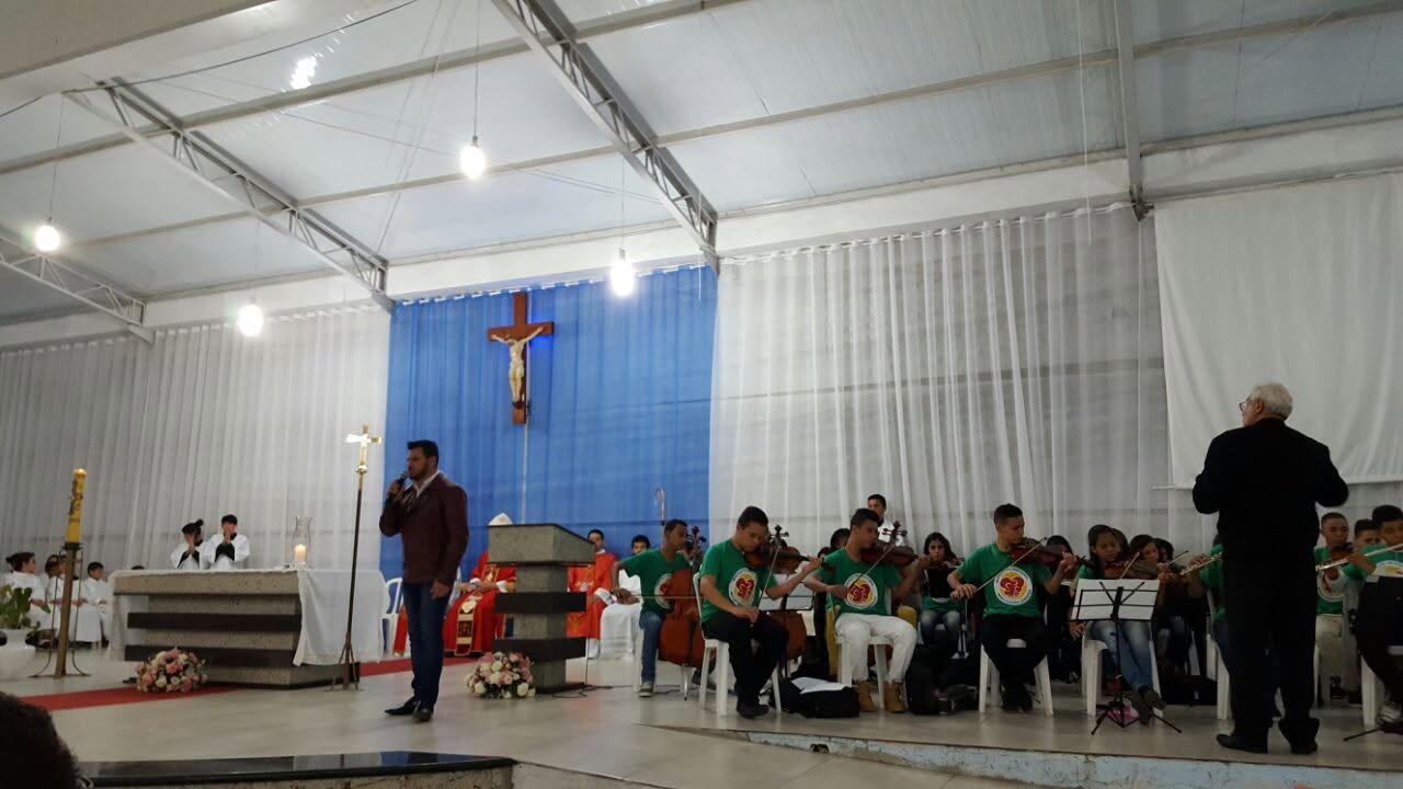 Orquestra jovem uniformizada durante missa em ginásio